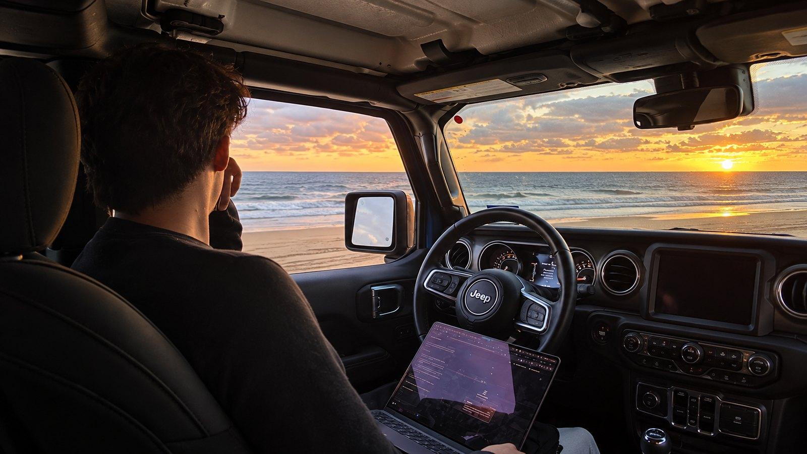 Trabajando desde un jeep frente al mar al atardecer